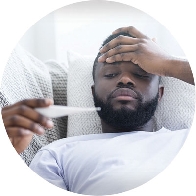 A man checks a thermometer to see if he has a fever, while holding his forehead.